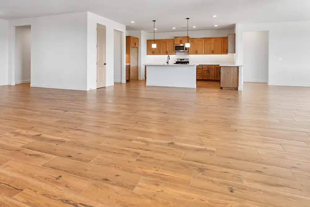 Ein geräumiger, leerstehender Raum mit Parkettboden und Deckenventilator.